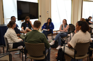 group of people sitting in a circle of chairs having a discussion