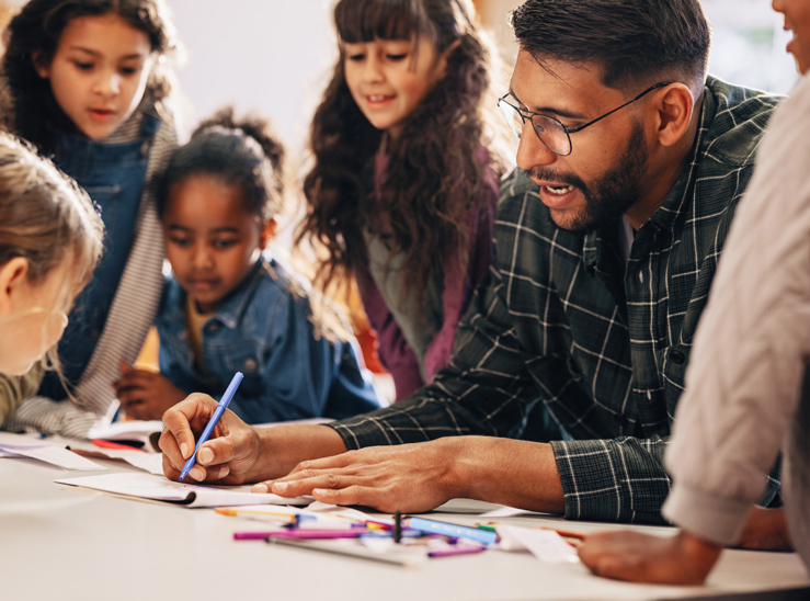 Man teaches his students how to draw in a primary school class stock photo